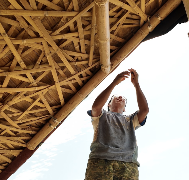 A crew member fitting laths under the woven bamboo roof at El Diviso