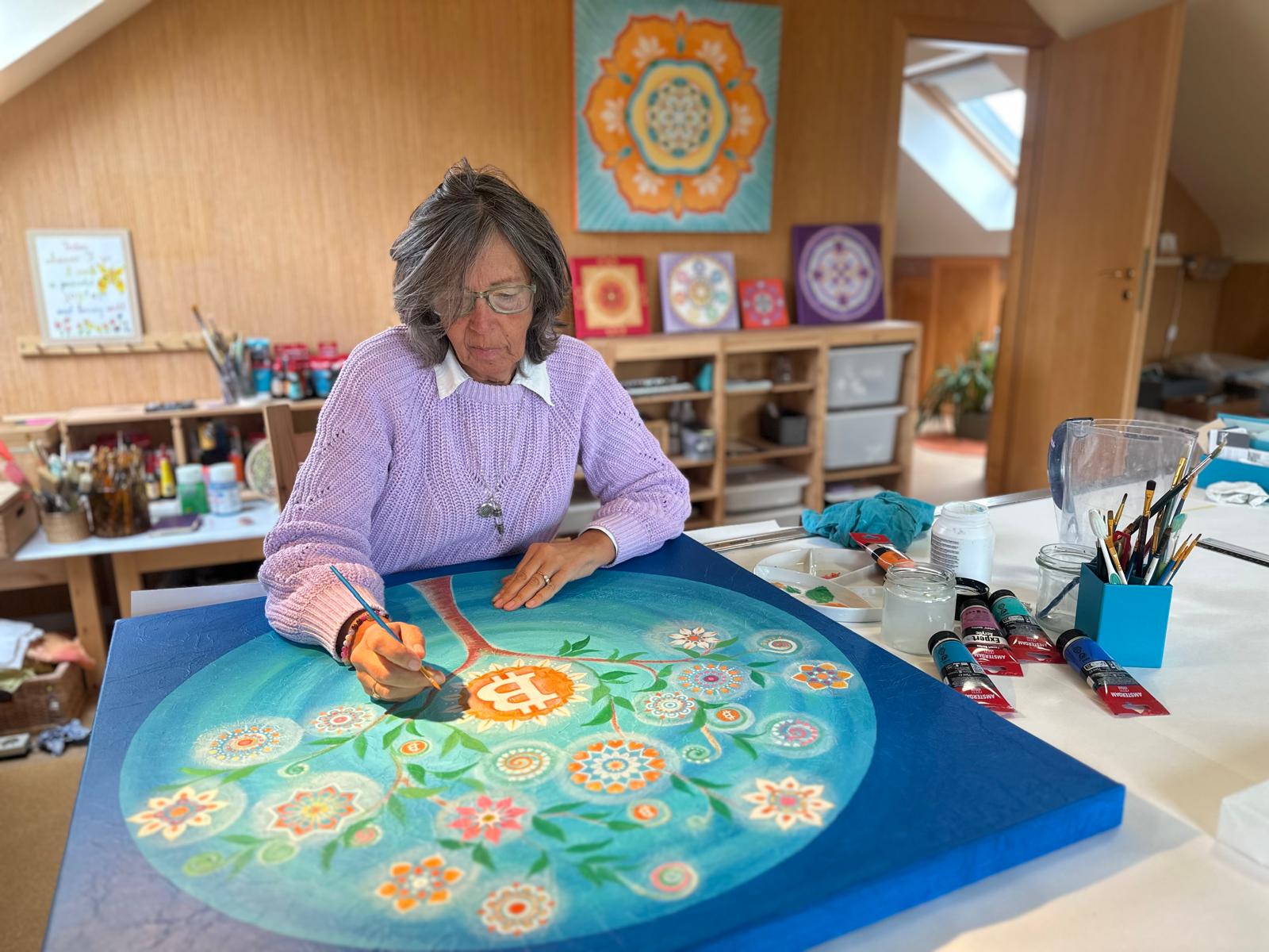Nala painting the Tree of Life mandala with Bitcoin at its center